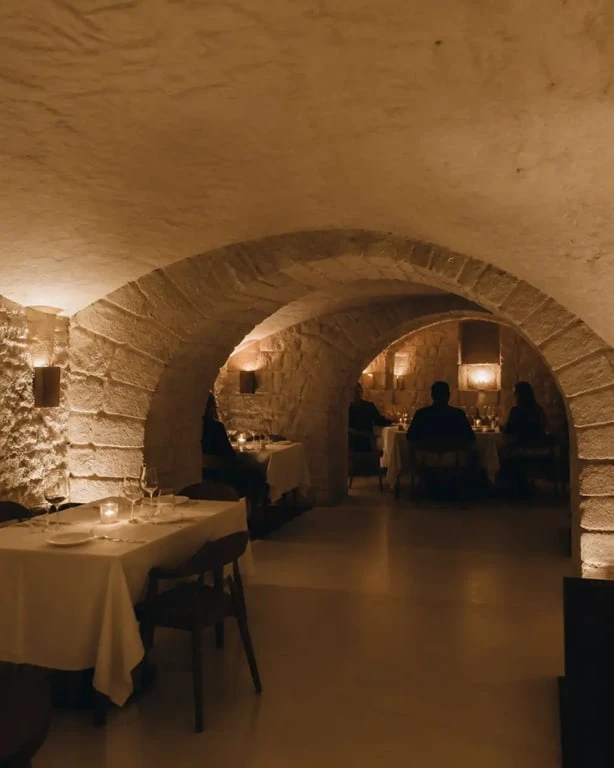 Caveau parisien sous voûtes en pierre avec dîner intimiste et lumière tamisée