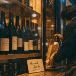 Nicolas cave a vin à Paris : vitrine de caviste, bouteilles et vendeur